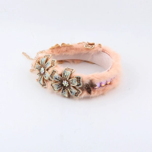 Detail van roze hoofdband van imitatiebont met strassbloemen en kralenkwastjes
