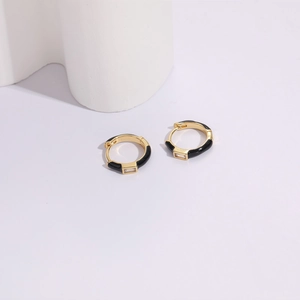 Detailed view of gold hoop earring with black enamel and a rectangular cubic zirconia