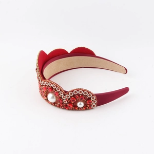 Close-up of red rhinestone headband with pearls and gold beads on red silk base
