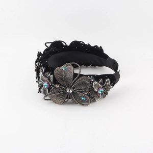 Detail of black velvet headband featuring floral embroidery and colorful rhinestone crystals