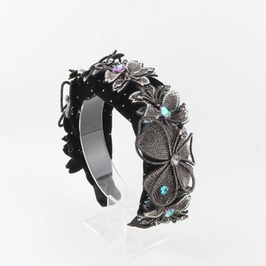Close-up of black velvet headband with rhinestone floral patterns and purple crystals