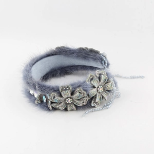 Detail van een pluche grijze hoofdband met kristallen bloemen en elegante kralen