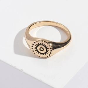 Detalle de un anillo de sello vintage dorado con tótem de sol negro y estilo bohemio
