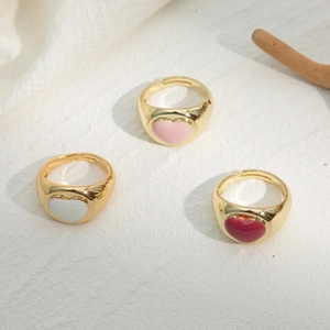 Vista detallada de tres anillos vintage de esmalte de corazón sobre fondo de piedra natural