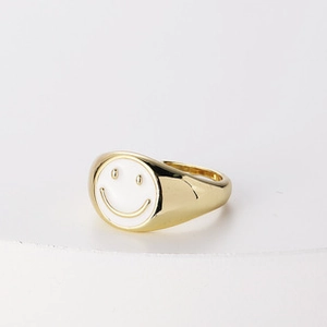 Detalle de anillo bañado en oro 14K con un smiley de esmalte blanco en una cara plana redonda