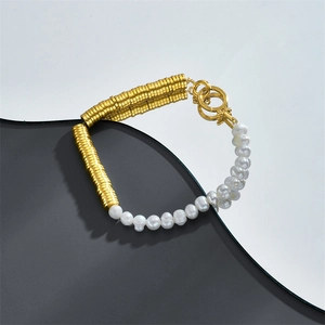 Freshwater pearl and gold disc beaded bracelet with OT toggle clasp on a reflective surface