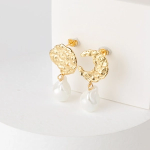 Detail of asymmetric gold hammered metal earrings with elegant baroque pearl pendants