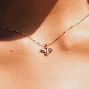Collier élégant doré avec pendentif abeille et chaîne fine porté par une femme