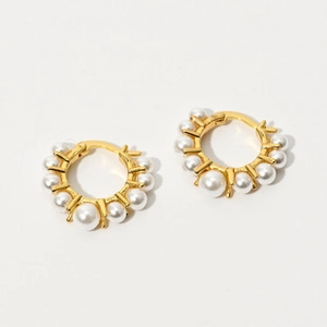Detail view of U-shaped gold earrings with gradient freshwater pearls on white background