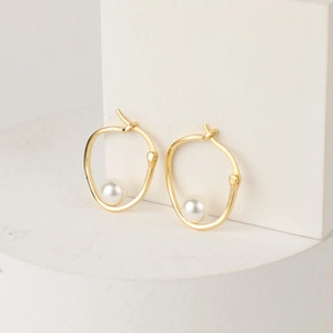 Detailed macro view of 14K gold plated hoop earrings with white pearl on stone base