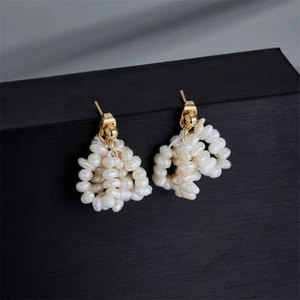 Macro detail of U-shaped earrings with white freshwater pearl clusters and 14K gold plating
