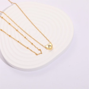 Detail of 18K gold plated heart necklace with zircon initial A on stone display