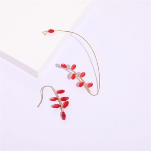 Détail de boucles d'oreilles artisanales avec perles rouges et tissage de fil doré