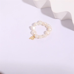 Baroque freshwater pearl ring with gold letter P pendant on minimalist pink background