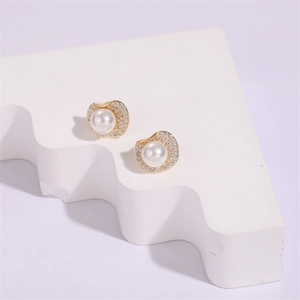 Detailed close-up of gold stud earrings with central pearl and pavé set rhinestones