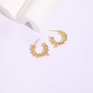 Detail of twisted gold metal C-shape hoop earrings with small pendant hook loops