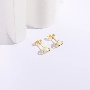 Detail shot of golden Saturn earrings featuring white opal stones on white stone blocks