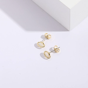Detail of Saturn-shaped gold opal stud earrings with sharp shadows on white stone