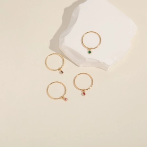 Minimalist gold adjustable rings featuring colorful round zircon charms on a stone display