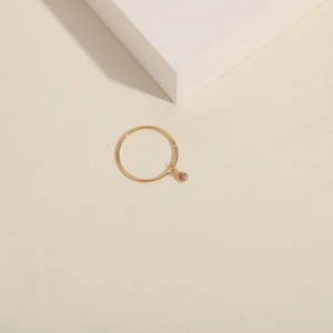 Close-up of a minimalist gold ring featuring a delicate round pink gemstone charm
