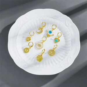 Detailansicht der goldenen Ohrringe mit Emaille-Auge und Zirkonia-Anhängern auf einem Tablett