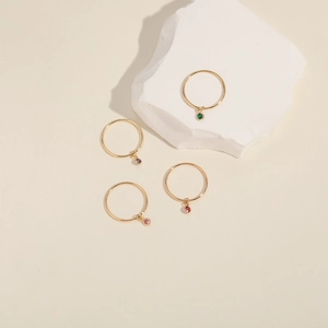 Set of four minimalist gold-plated adjustable rings with small colorful gemstone charms