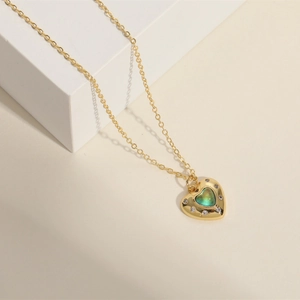 Gold heart pendant necklace with green cat-eye stone and small white zircon accents