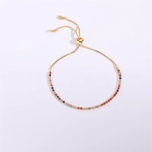 Détail du bracelet en pierres multicolores avec fermoir coulissant doré sur fond blanc