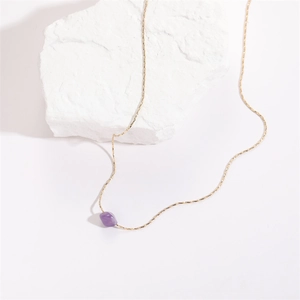 Minimalist gold necklace with irregular purple amethyst crystal pendant on stone base