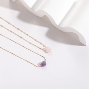 Detail of pink and purple crystal teardrop pendants on elegant gold twist chains