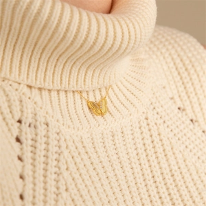 Close-up of 14K gold butterfly pendant necklace with micro zircon on white sweater