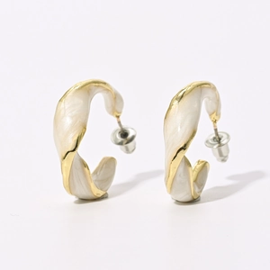 Detail of French vintage gold-plated C-shape twisted earrings with cream enamel finish