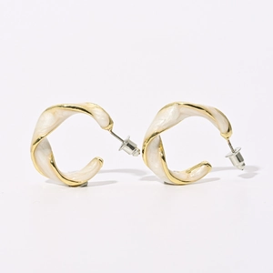Detailed macro view of vintage C-shape twisted hoop earrings with cream enamel and gold rim