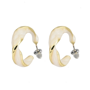 Detailed view of gold twist C-shape earrings with white enamel finish and silver studs