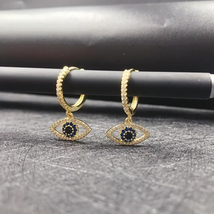 Macro detail of 14K gold evil eye hoop earrings featuring blue zircons and white crystals