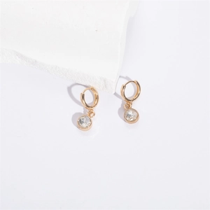 Macro detail of gold hoop earrings with clear round gemstone pendants on white stone