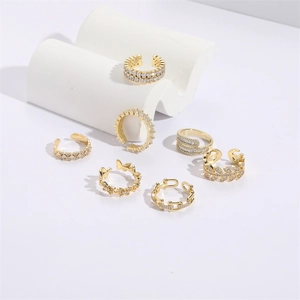 Detailed view of six gold-plated butterfly and zircon rings on white display props
