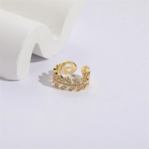 Macro shot of gold olive leaf ring with cubic zirconia on white decorative stones