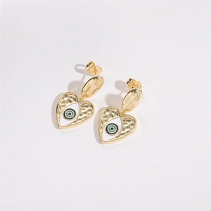 Detail of gold heart earrings with hammered texture and evil eye enamel design