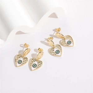 Detailed view of heart-shaped evil eye earrings with golden hammered metal texture