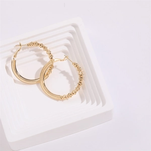 Exaggerated 14K gold chunky twist hoop earrings with knurled texture on white platform