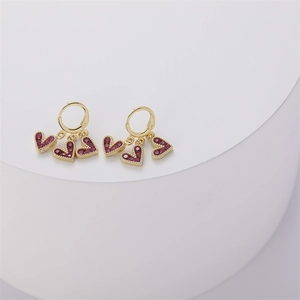 Detail of 14K gold-plated huggie earrings with three magenta heart-shaped cubic zirconia
