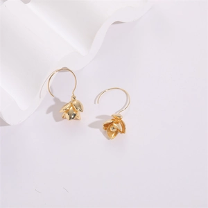 Dettaglio di orecchini a fiore in oro 14K con petali stratificati su sfondo bianco