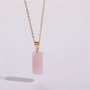 Gros plan détaillé du pendentif en quartz rose cylindrique sur une chaîne dorée fine