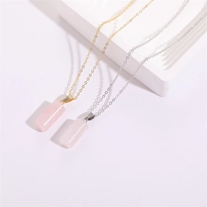 Gros plan de pendentifs cylindres en cristal rose sur chaînes dorées et argentées
