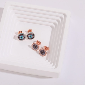 Détail de boucles d'oreilles Evil Eye et Sunburst en or rose avec micro-pavage zircon