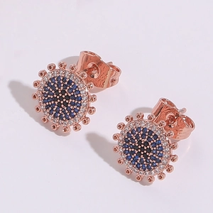 Gros plan de boucles d'oreilles œil porte-bonheur en or rose serties de zircons bleus