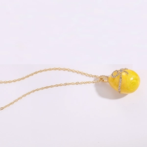 Macro detail of yellow enamel egg pendant with gold bow and sparkling zircons