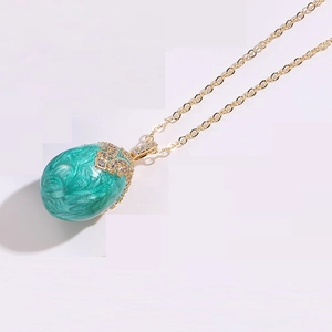 Detail of teal enamel egg pendant with 14K gold openwork and sparkling zircon inlays