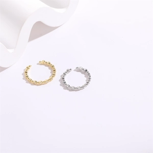 Detail of gold and silver open rings set with sparkling cubic zirconia on white waves
